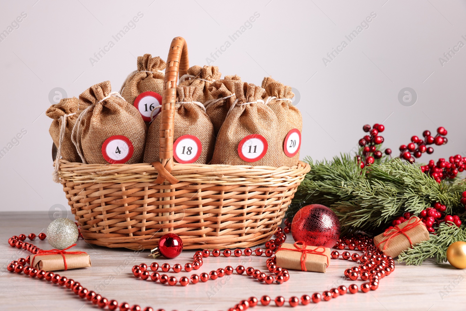 Photo of Christmas advent calendar with gifts in wicker basket and decor on wooden table