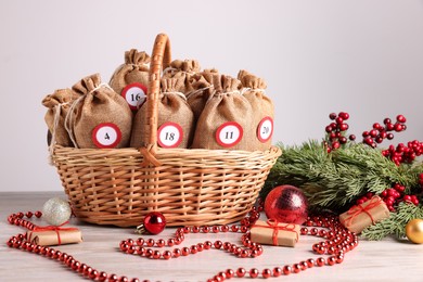 Photo of Christmas advent calendar with gifts in wicker basket and decor on wooden table