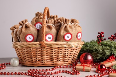 Photo of Christmas advent calendar with gifts in wicker basket and decor on wooden table