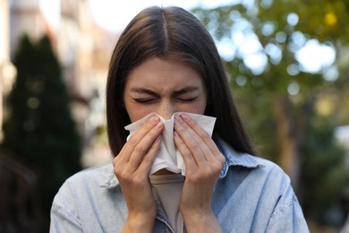 Young woman with runny nose in park