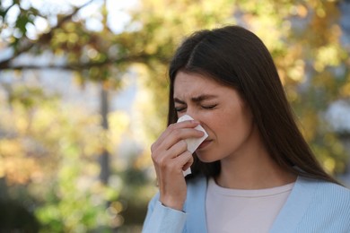 Photo of Woman with runny nose in park, space for text