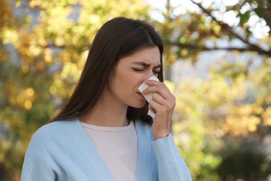 Photo of Woman with runny nose in park, space for text