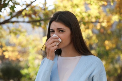 Photo of Woman with runny nose in park, space for text