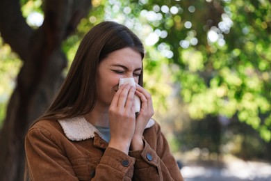 Photo of Woman with runny nose in park, space for text