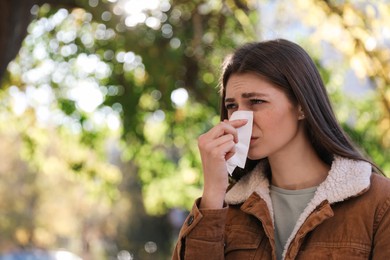 Photo of Woman with runny nose in park, space for text