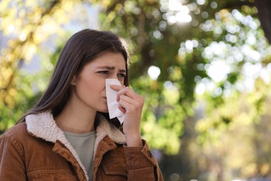 Photo of Woman with runny nose in park, space for text