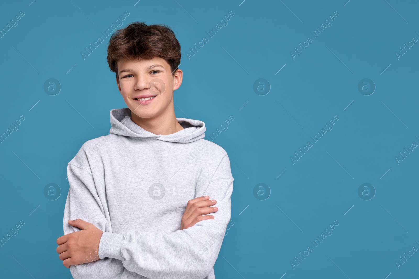 Photo of Portrait of happy teenage boy on light blue background, space for text