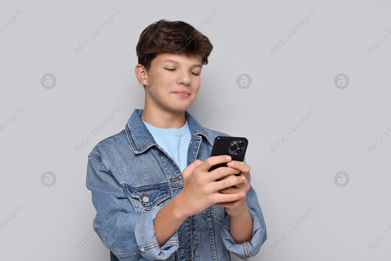 Photo of Teenage boy with smartphone on light grey background