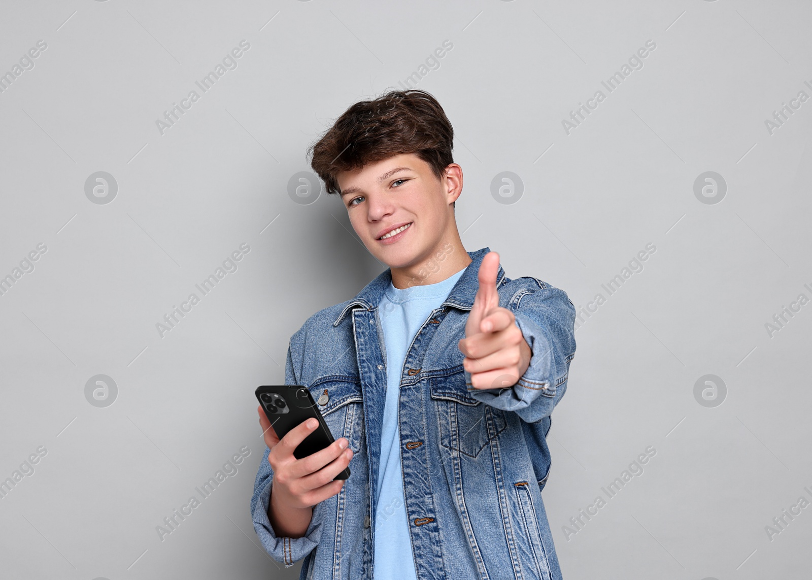 Photo of Teenage boy with smartphone on light grey background