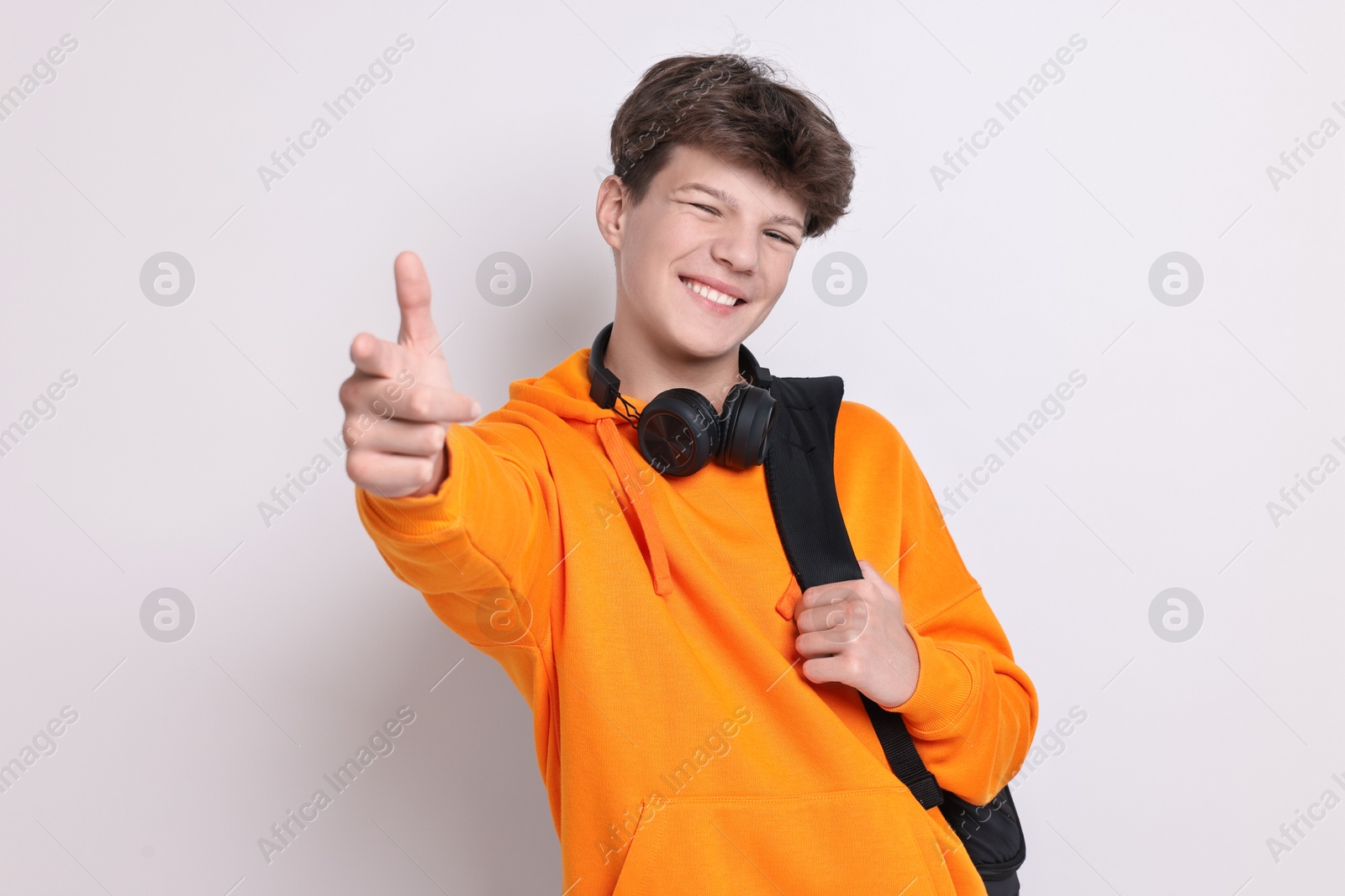 Photo of Teenage boy with headphones and backpack on white background