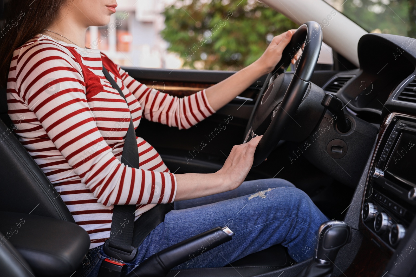 Photo of Pregnant woman with safety belt driving car, closeup