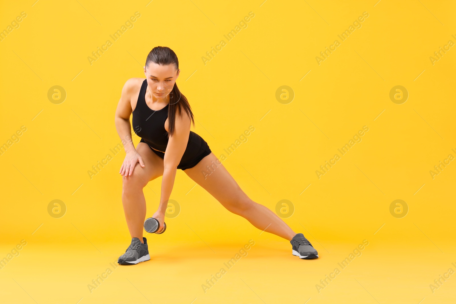 Photo of Woman exercising with dumbbell on orange background, space for text