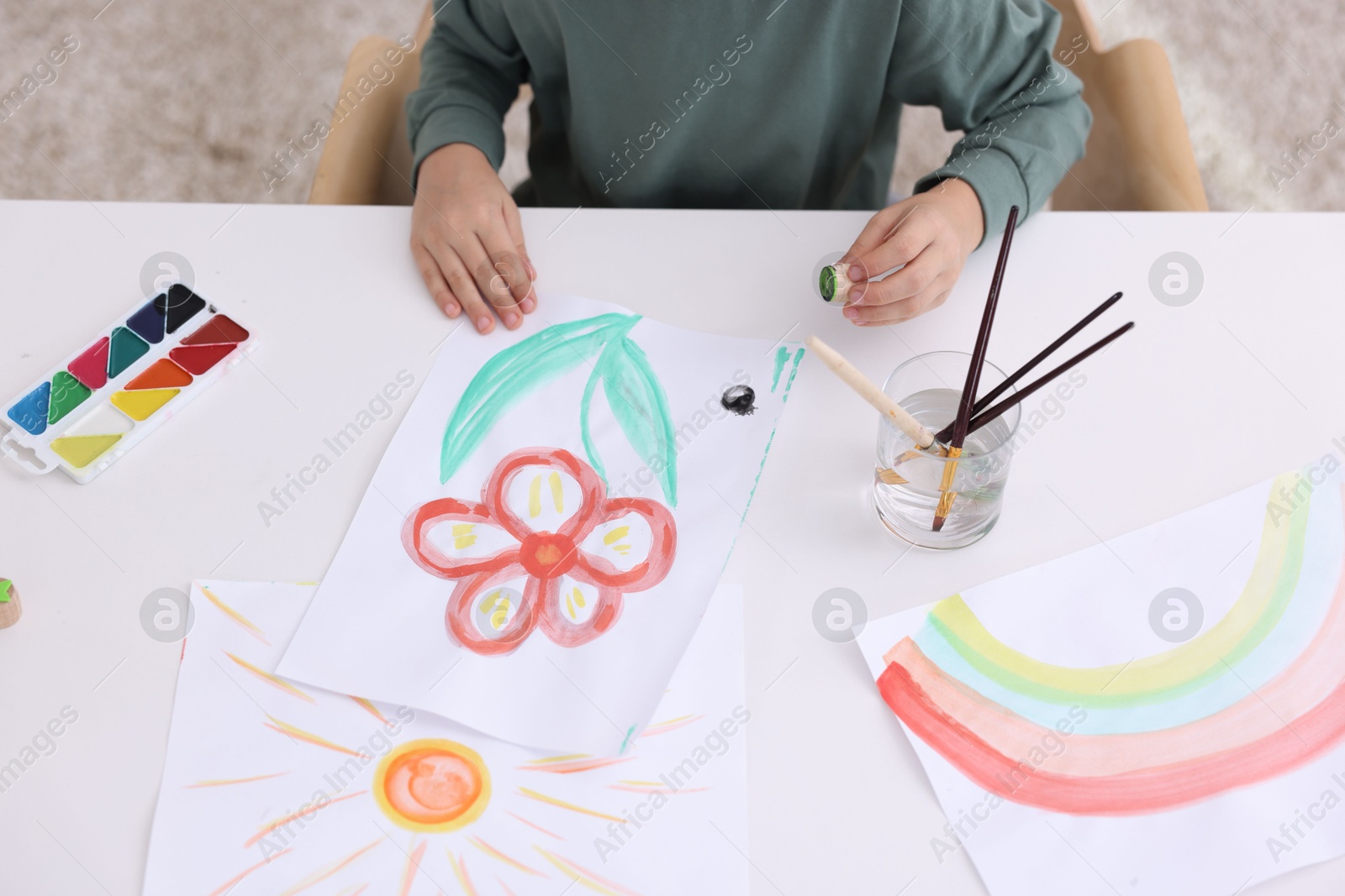 Photo of Little boy drawing at white table indoors, closeup