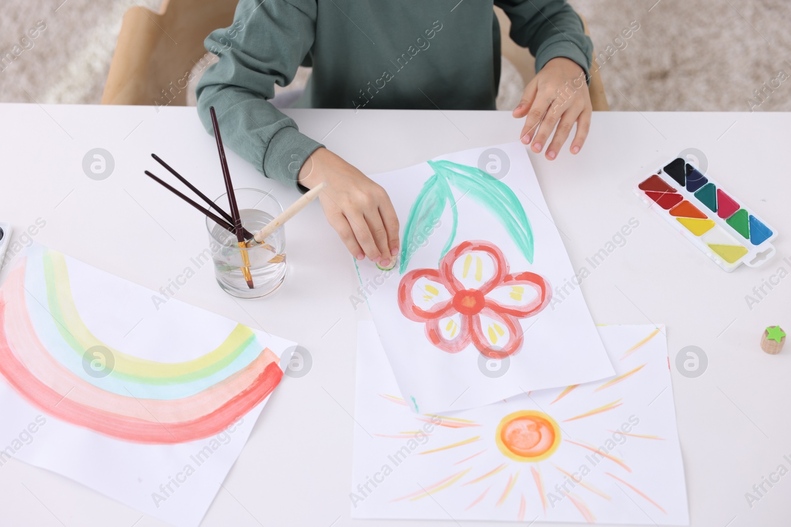 Photo of Little boy drawing at white table indoors, closeup