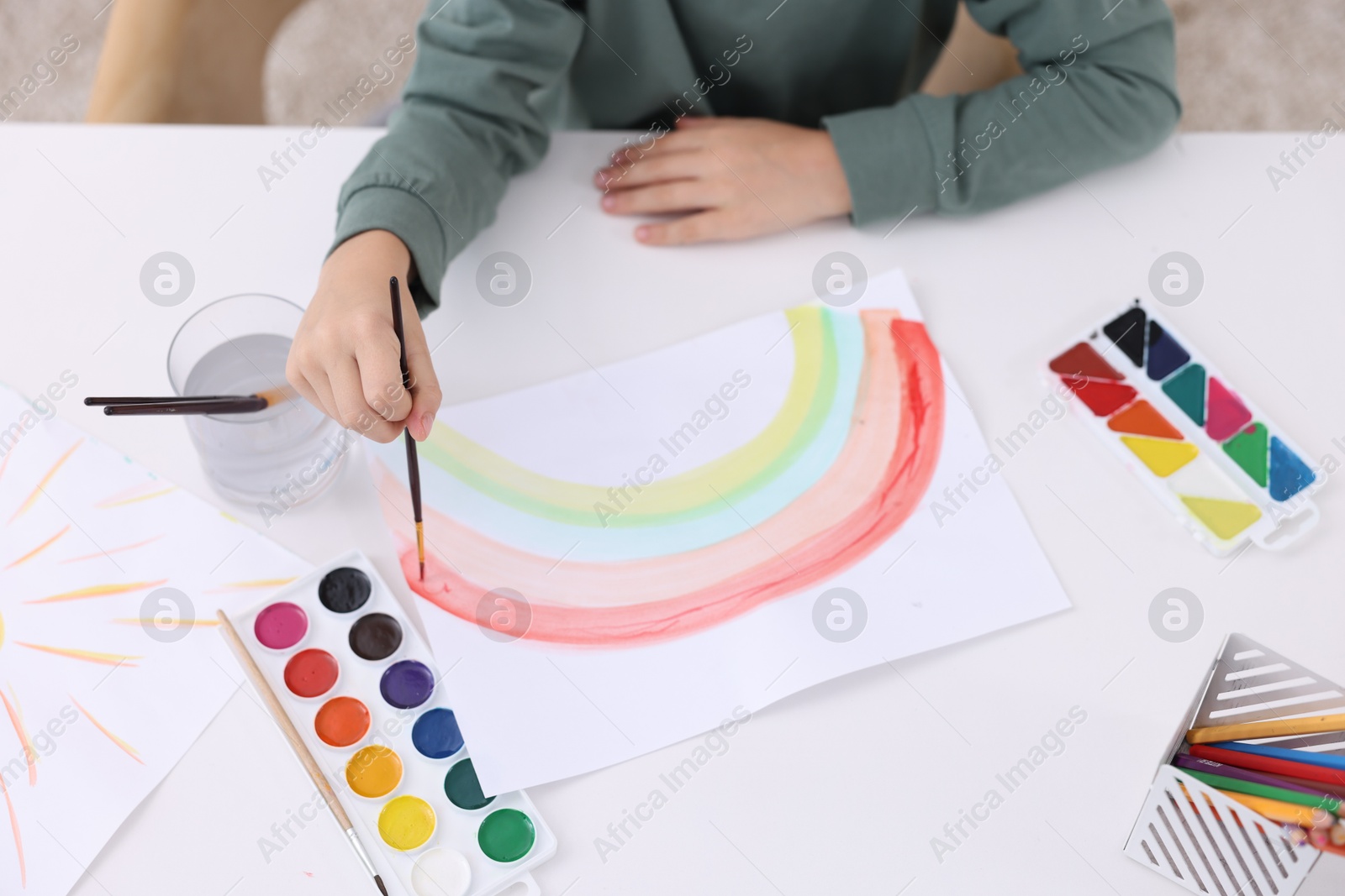 Photo of Little boy drawing at white table indoors, closeup