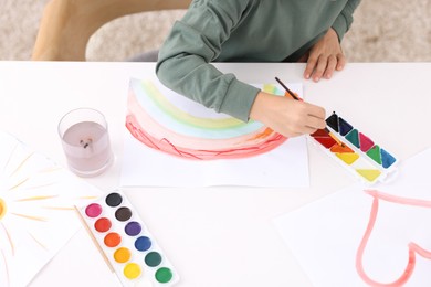 Photo of Little boy drawing at white table indoors, closeup