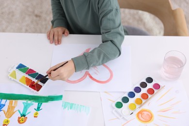 Photo of Little boy drawing at white table indoors, above view