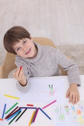 Photo of Happy boy drawing at white table indoors