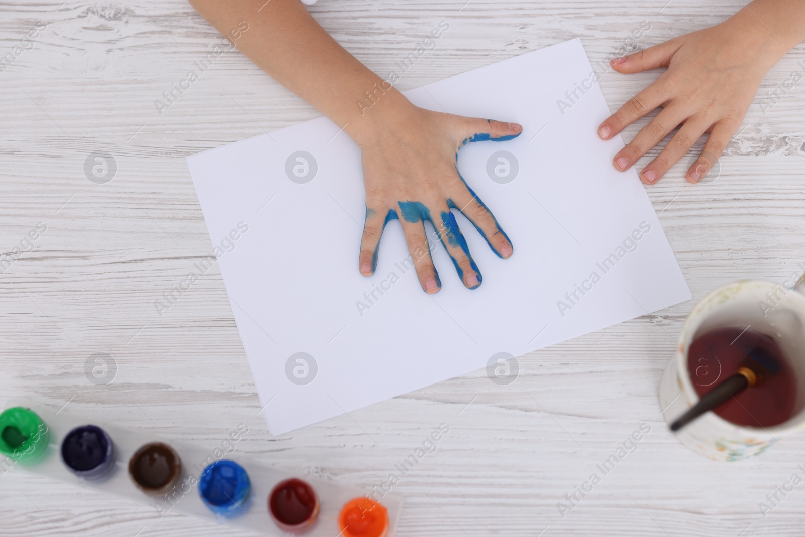 Photo of Boy drawing with palm at light wooden table, top view