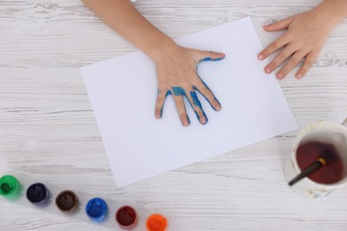 Photo of Boy drawing with palm at light wooden table, top view