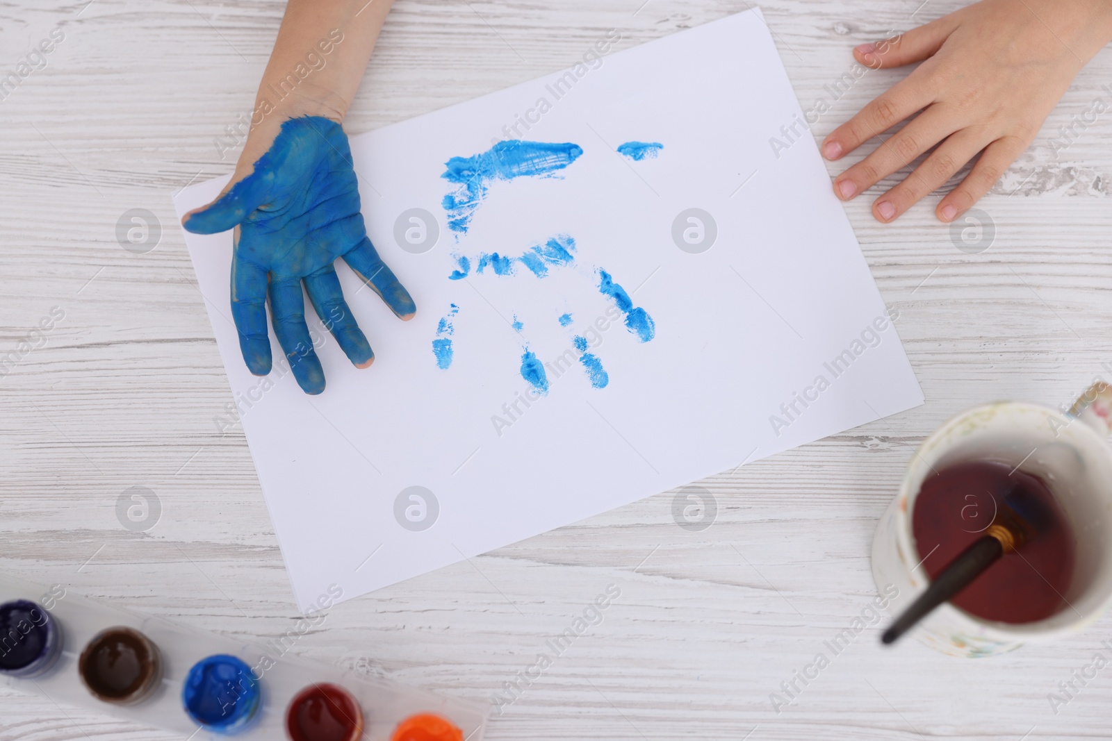 Photo of Boy drawing with palm at light wooden table, top view