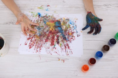 Photo of Boy drawing with palm at light wooden table, top view