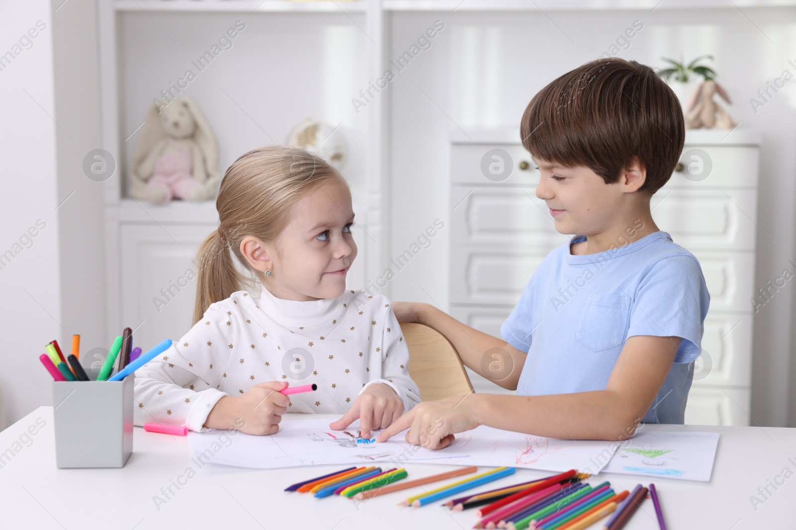 Photo of Cute children drawing at white table in kindergarten