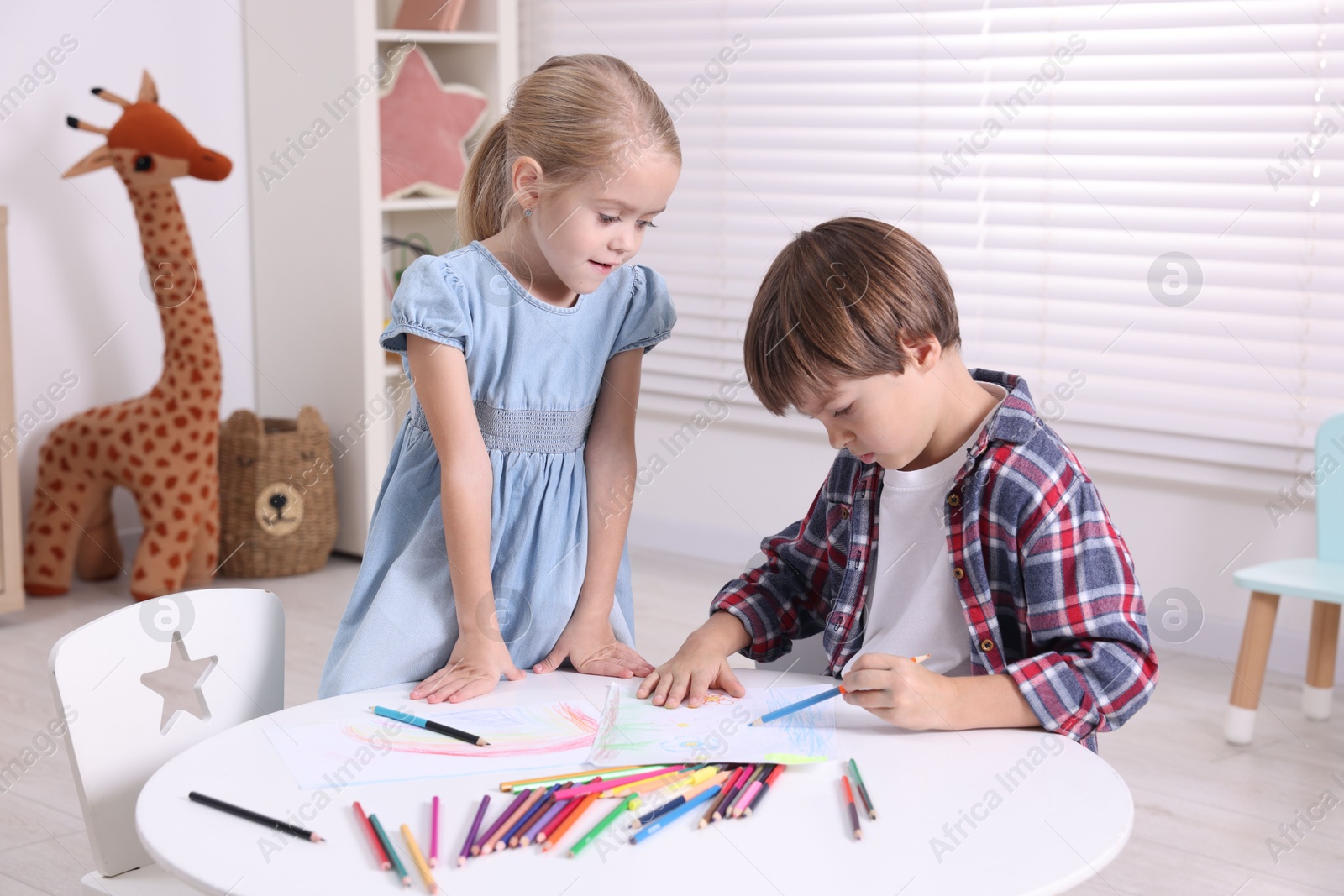 Photo of Cute children drawing at white table in kindergarten