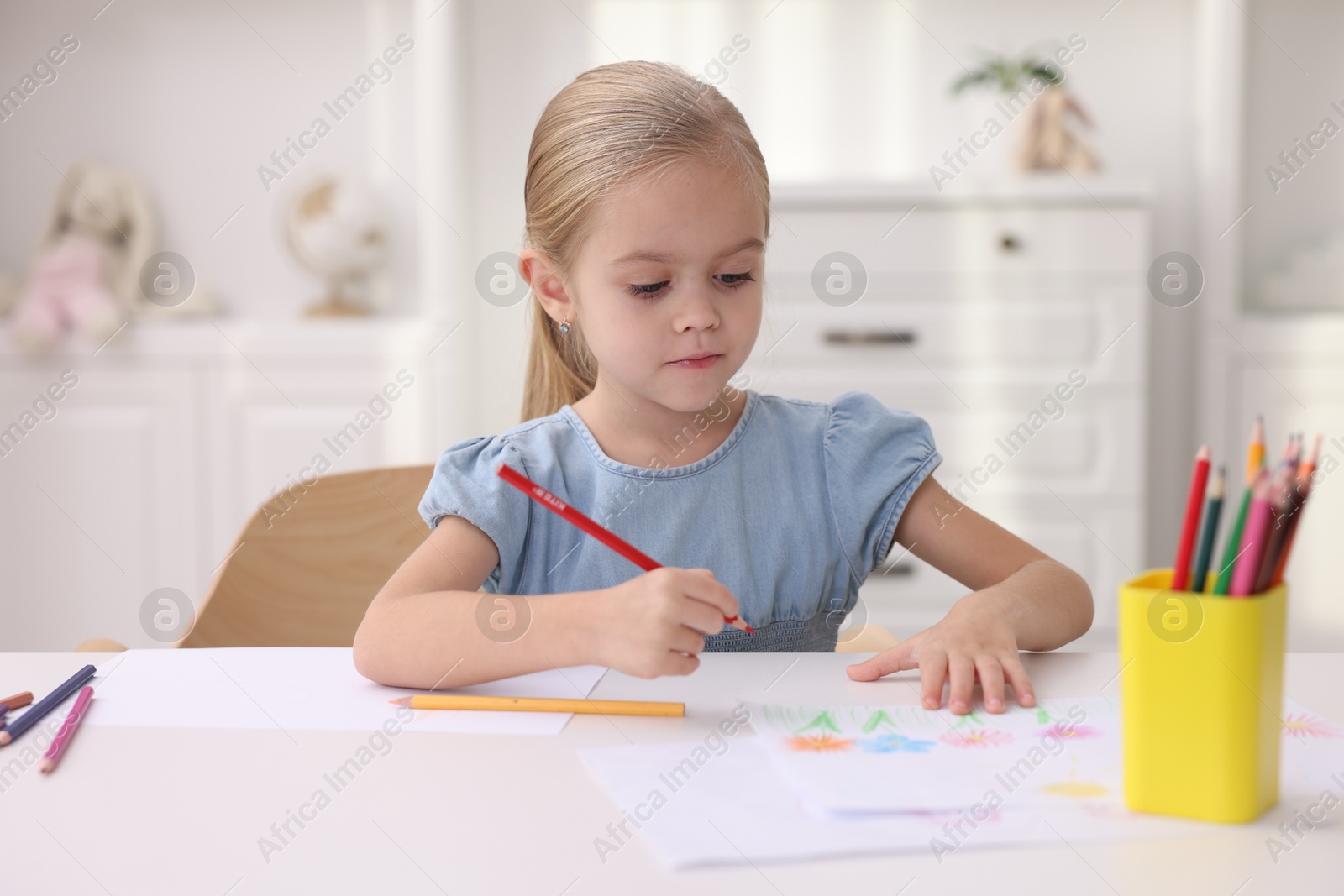 Photo of Cute girl drawing at white table in kindergarten