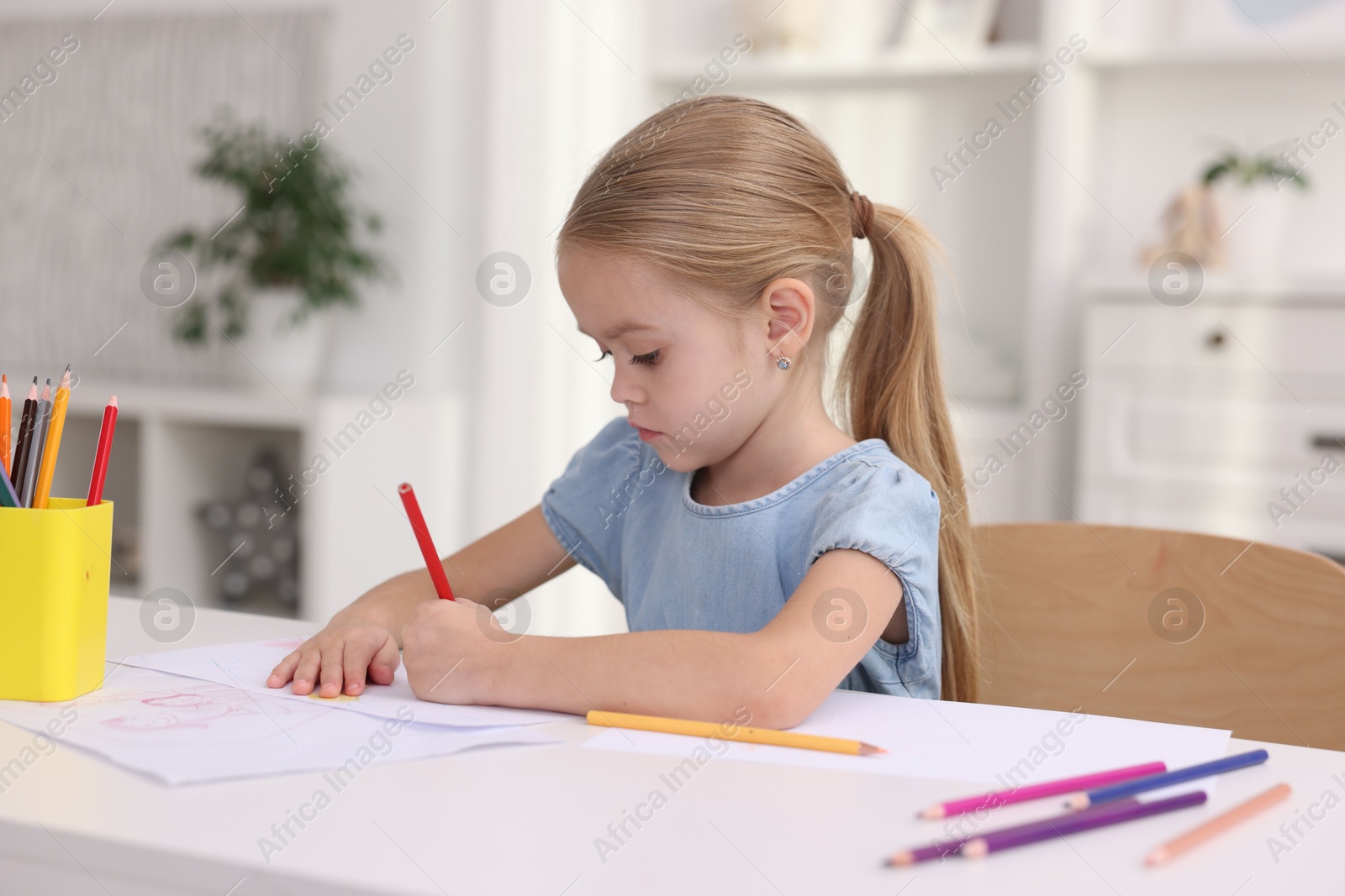 Photo of Cute girl drawing at white table in kindergarten