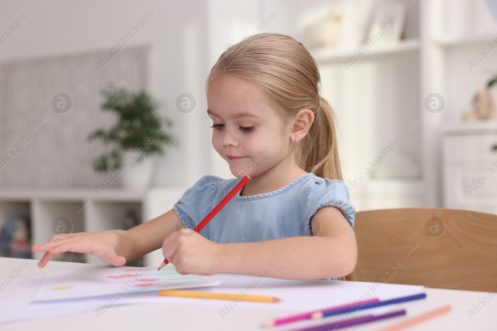 Photo of Cute girl drawing at white table in kindergarten