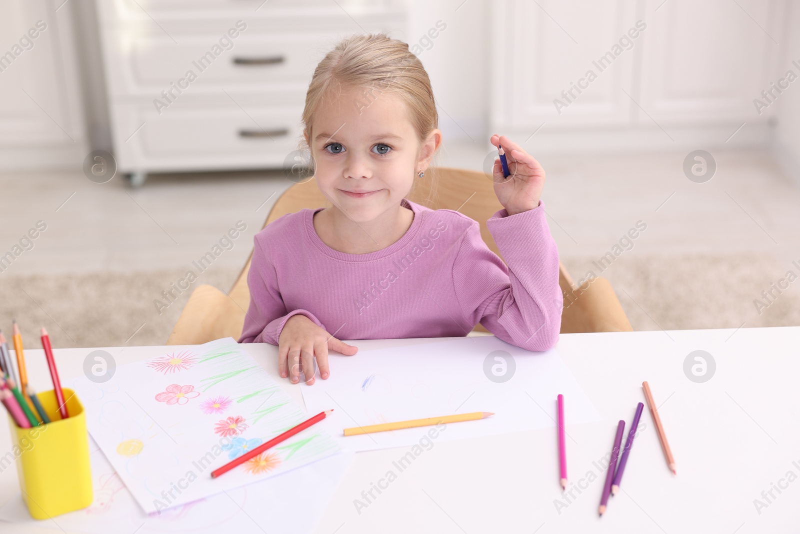 Photo of Cute girl drawing at white table in kindergarten