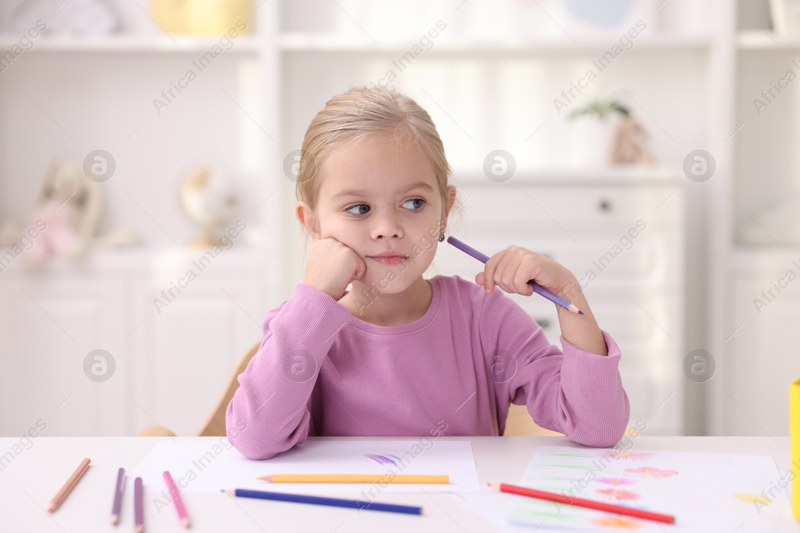 Photo of Cute girl at white table with drawing in kindergarten