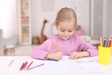 Photo of Cute girl drawing at white table in kindergarten