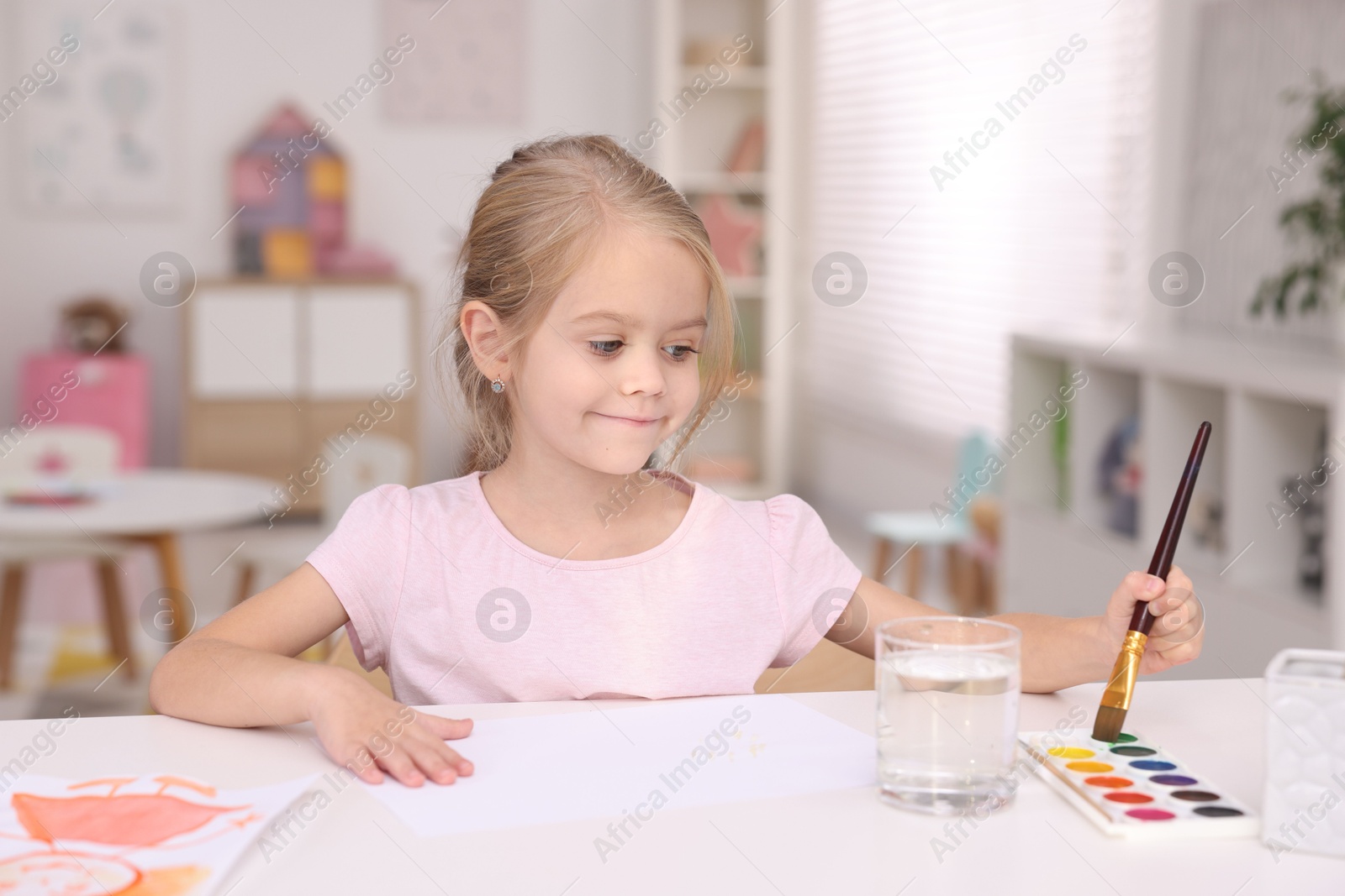 Photo of Cute girl drawing at white table in kindergarten