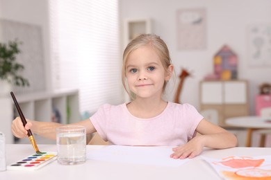 Photo of Cute girl drawing at white table in kindergarten