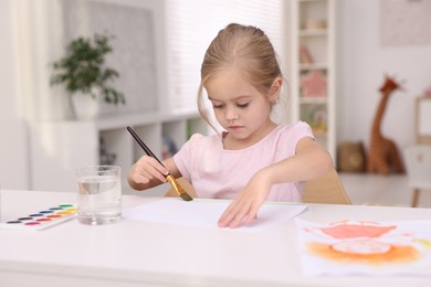 Photo of Cute girl drawing at white table in kindergarten