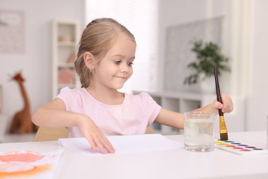 Cute girl drawing at white table in kindergarten