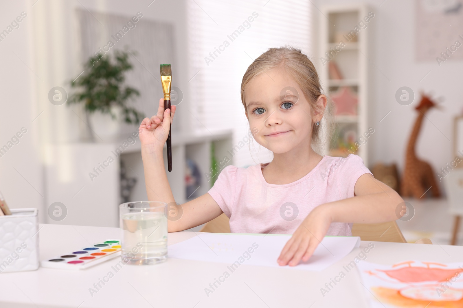 Photo of Cute girl drawing at white table in kindergarten