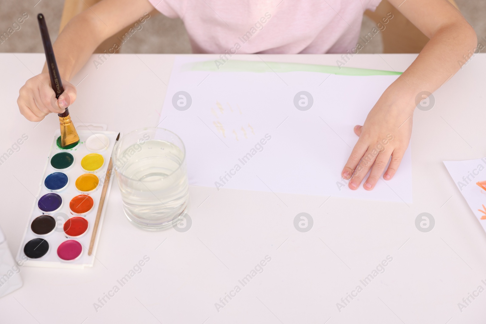 Photo of Girl drawing with paint at white table indoors, closeup