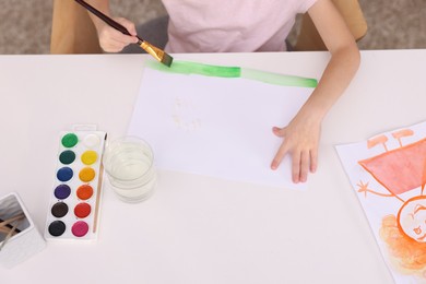 Photo of Girl drawing with paint at white table indoors, closeup