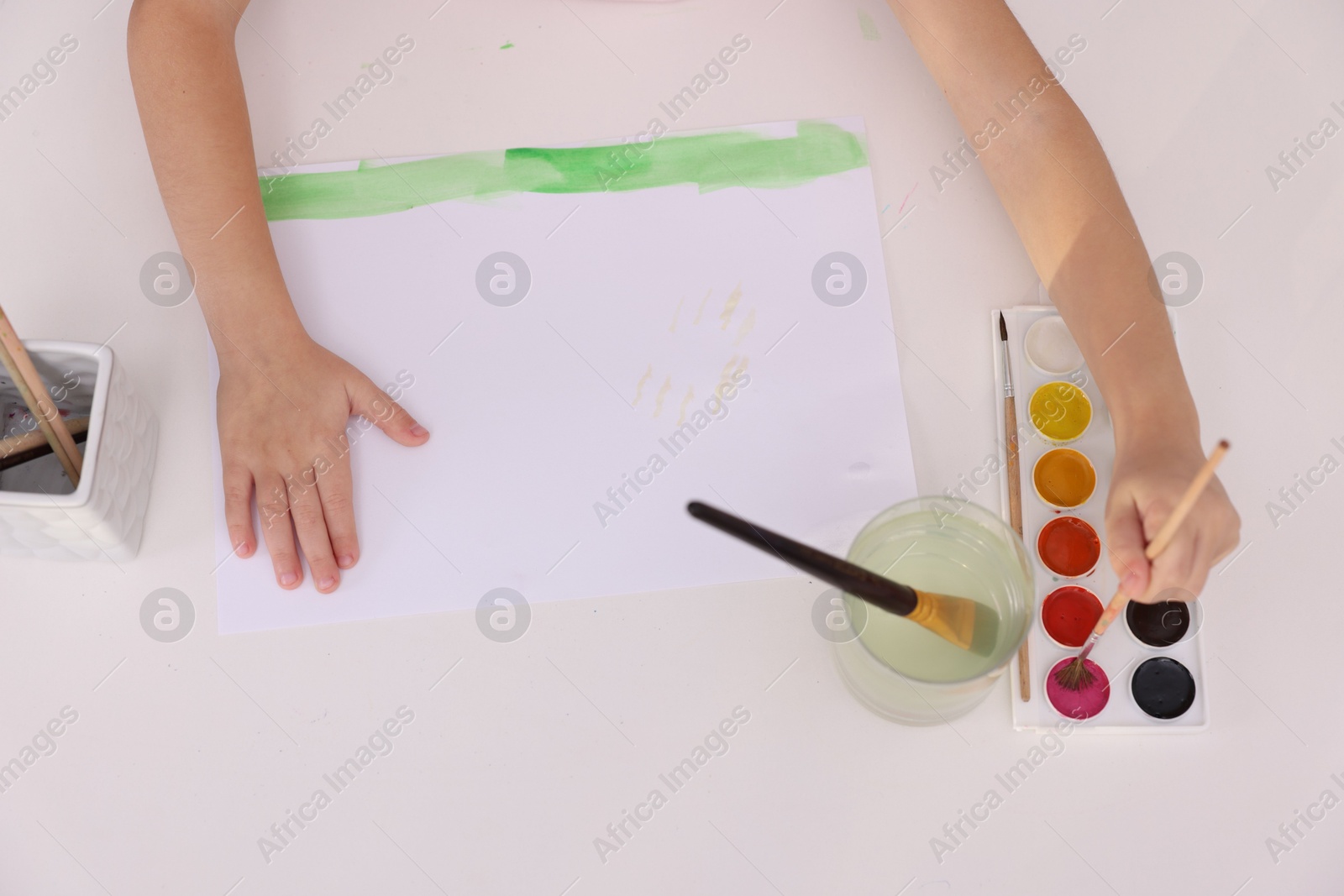 Photo of Girl drawing with paint at white table, above view