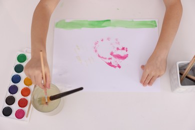 Photo of Girl drawing with paint at white table, above view