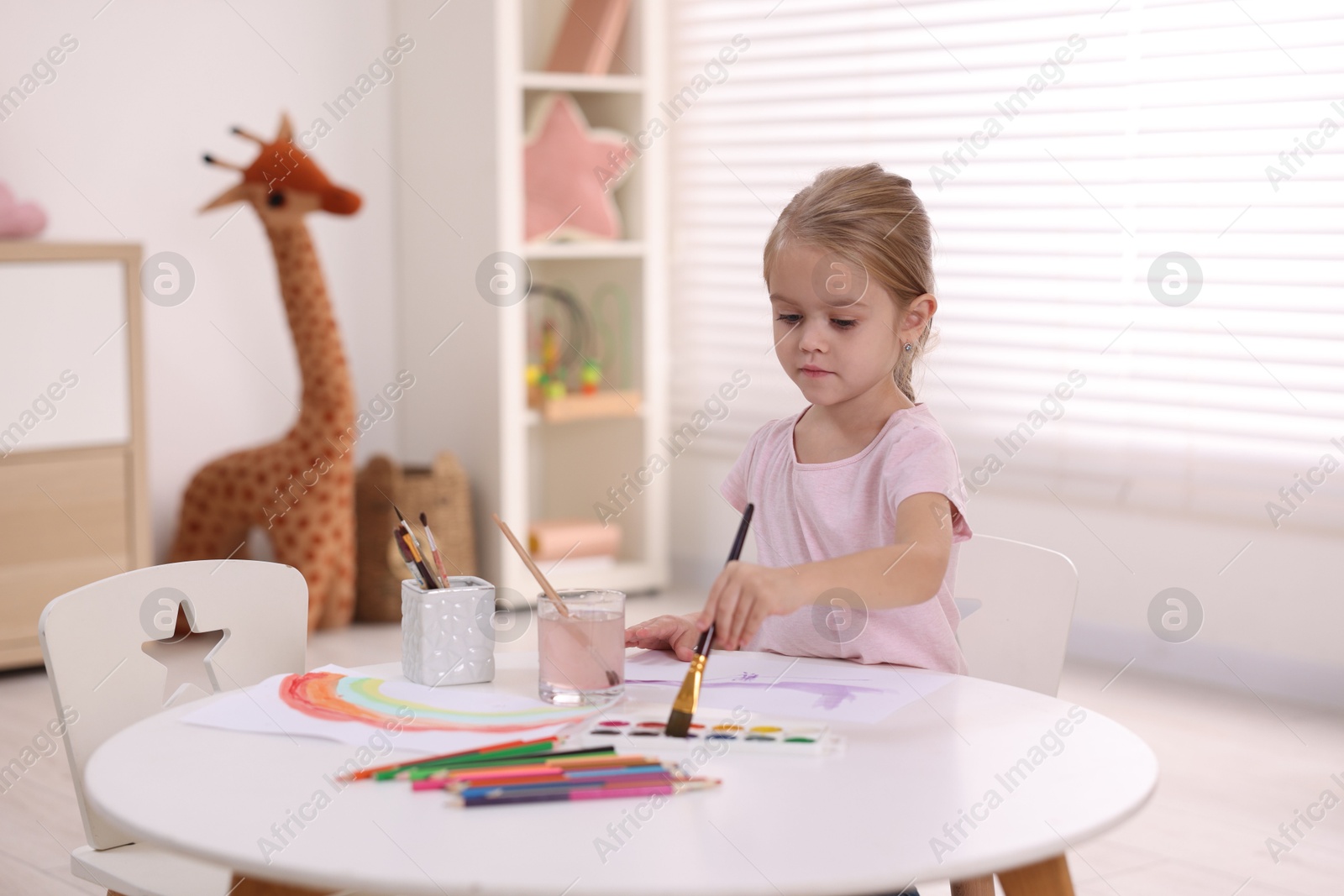 Photo of Cute girl drawing at white table in kindergarten