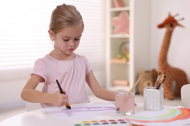 Photo of Cute girl drawing at white table in kindergarten