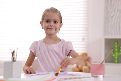 Photo of Cute girl drawing at white table in kindergarten