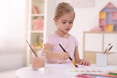 Photo of Cute girl drawing at white table in kindergarten