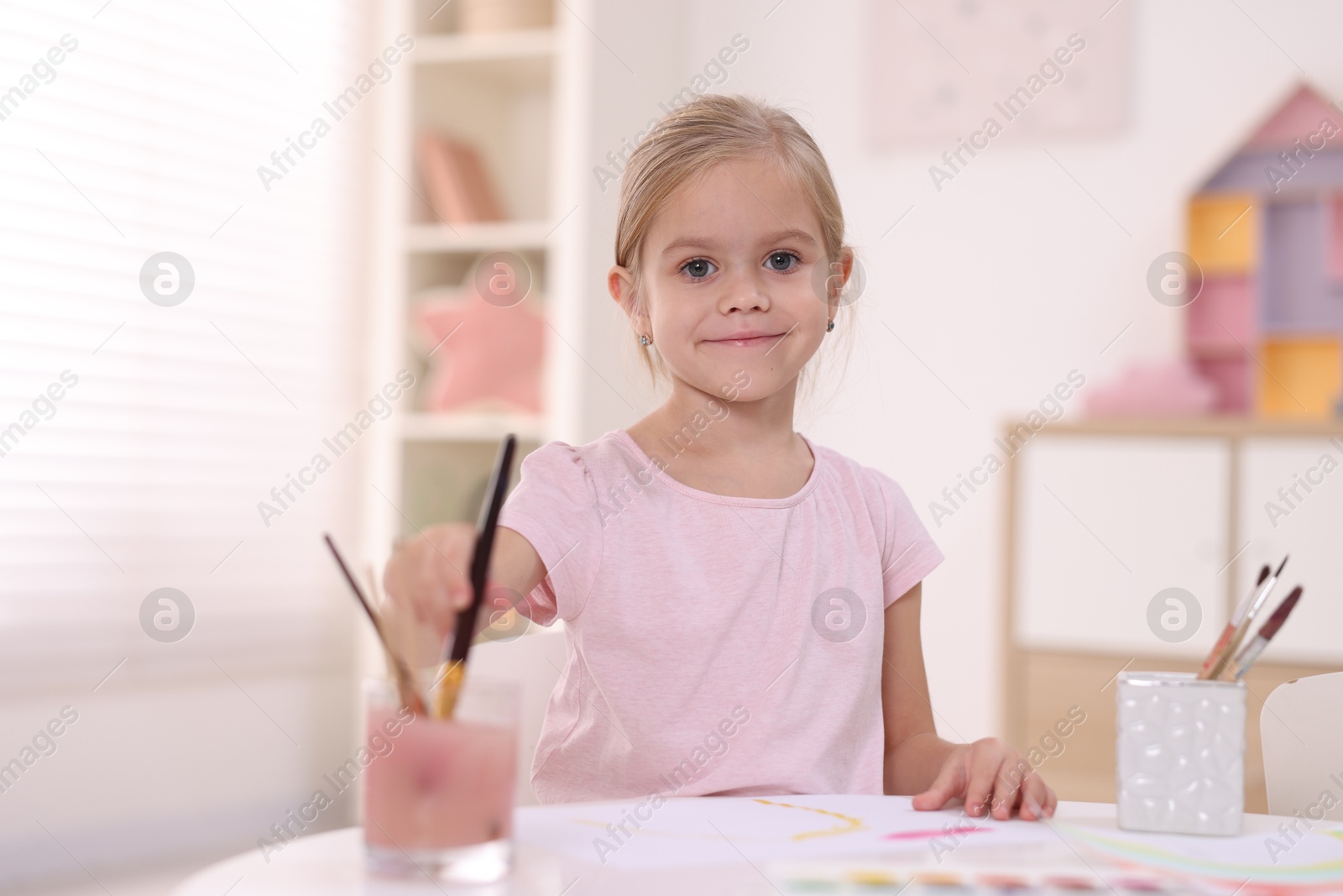 Photo of Cute girl drawing at white table in kindergarten