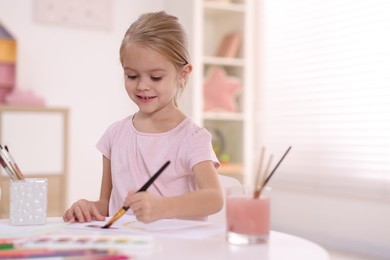 Photo of Smiling girl drawing at white table in kindergarten. Space for text