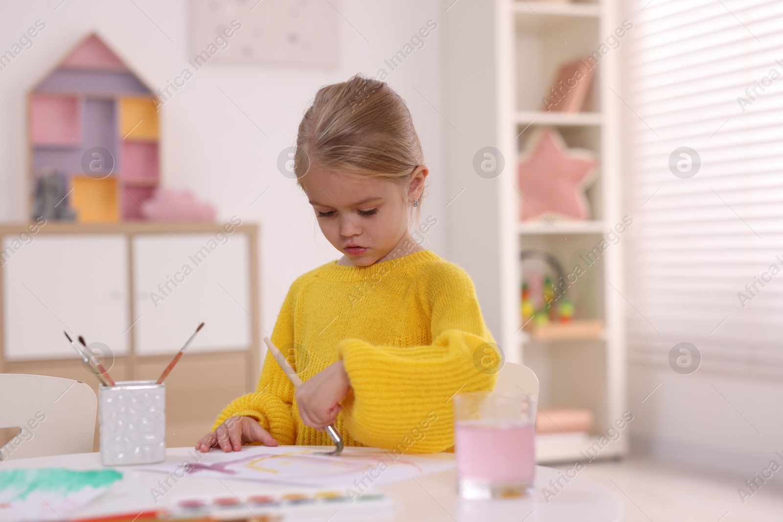 Photo of Cute girl drawing at white table in kindergarten